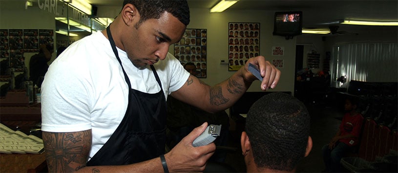 Male barber touching up client's cut with a clipper.